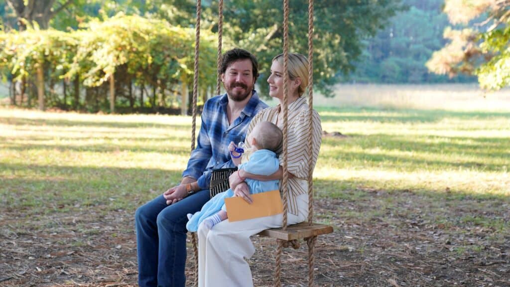 Emma Roberts and John Gallagher Jr hold their baby on a swing in Abandoned (2022).