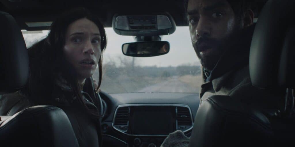 Katie Parker and Rahul Kohli look back in horror in Next Exit (2022).