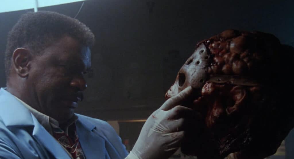 A medical examiner looking at the decapitated head of Jason Voorhees. 