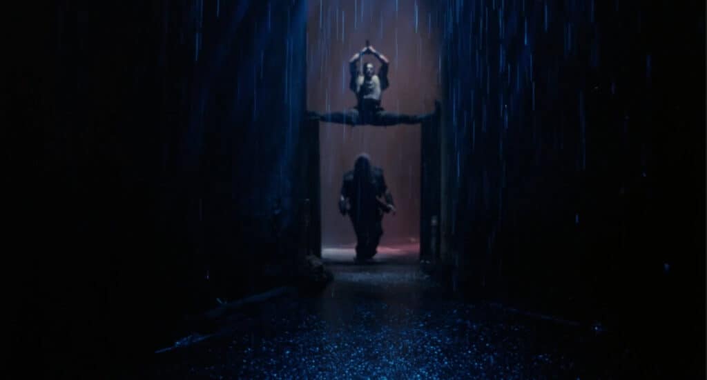 Jean Claude Van Damme doing the splits above someone